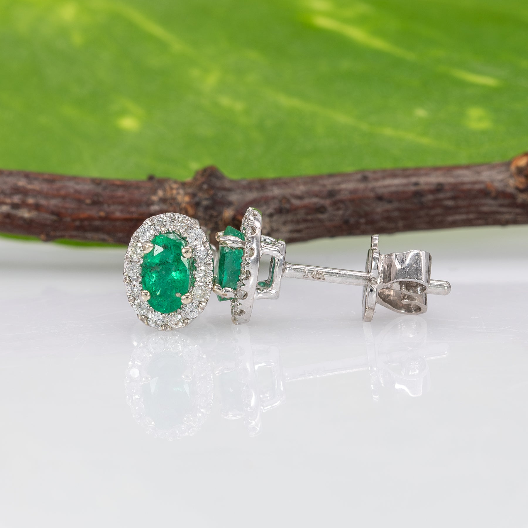 14K white gold emerald oval stud earrings with diamond halo