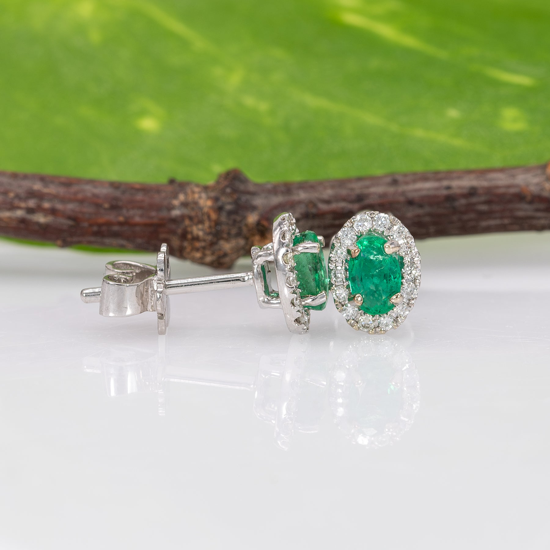 14K white gold emerald oval stud earrings with diamond halo